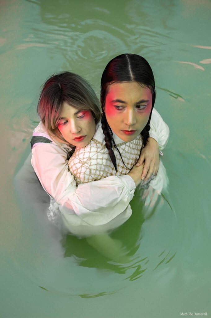 Dentdelion, le duo immergé jusqu’à la taille dans une eau verte, maquillage rouge autour des yeux